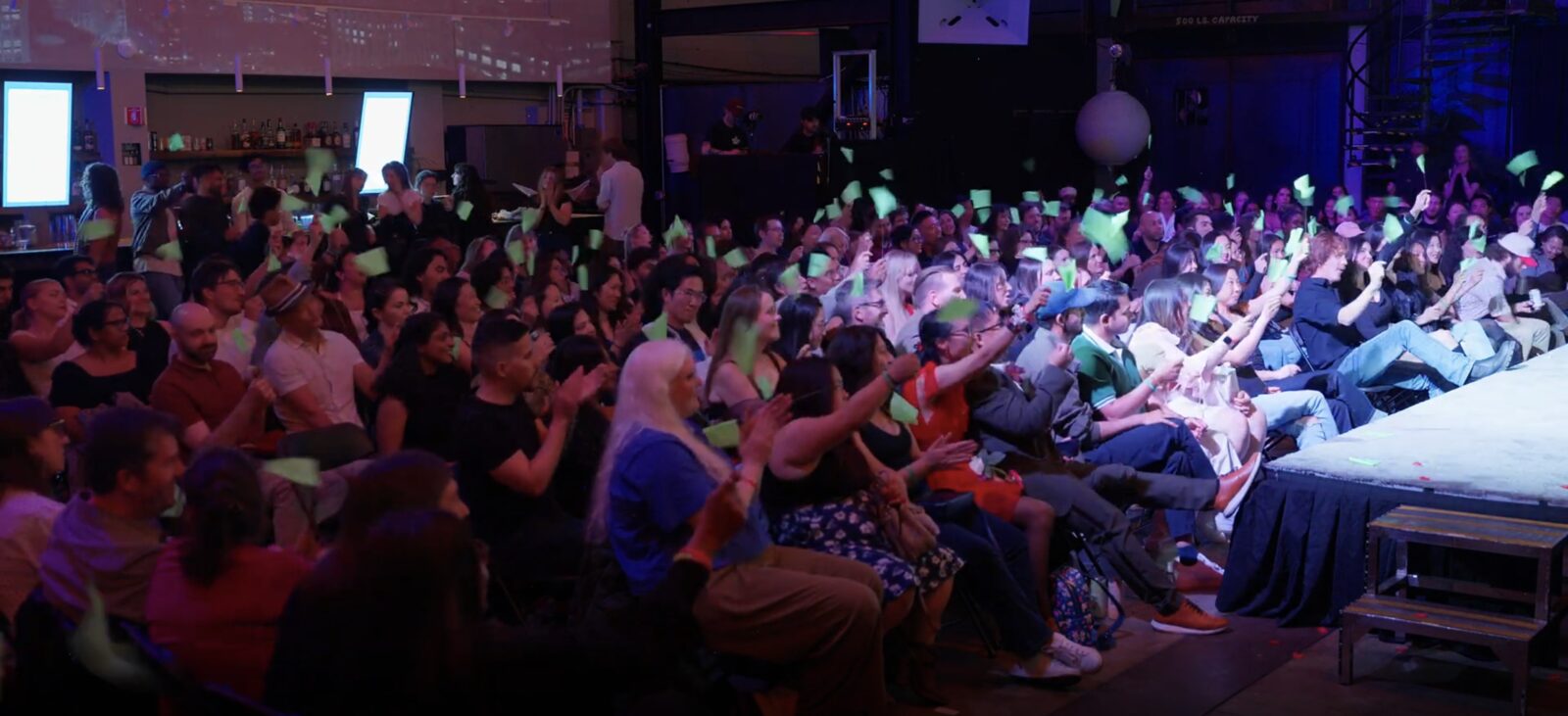 A packed, screaming audience under purple lights