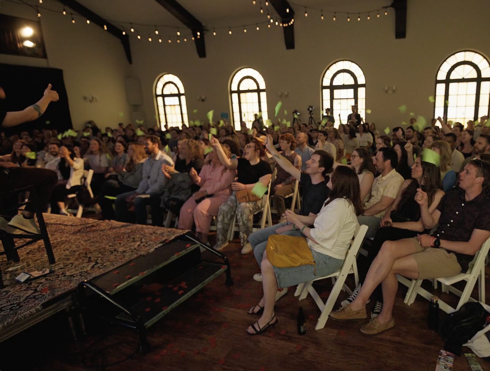 A sold-out room under arched windows, green flags up